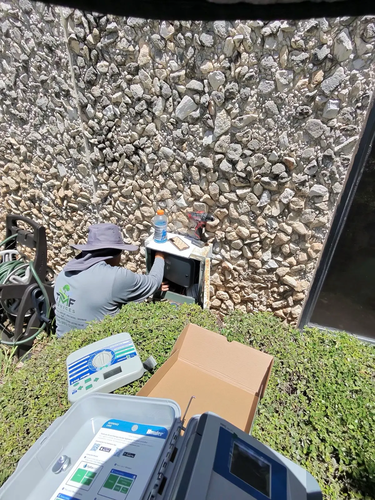 TMF Services crew member installing an irrigation controller on a property.