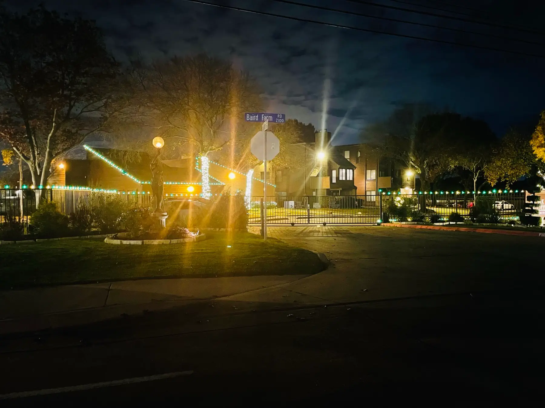 Perimeter lighting outlining a fenced property and trees after dark.